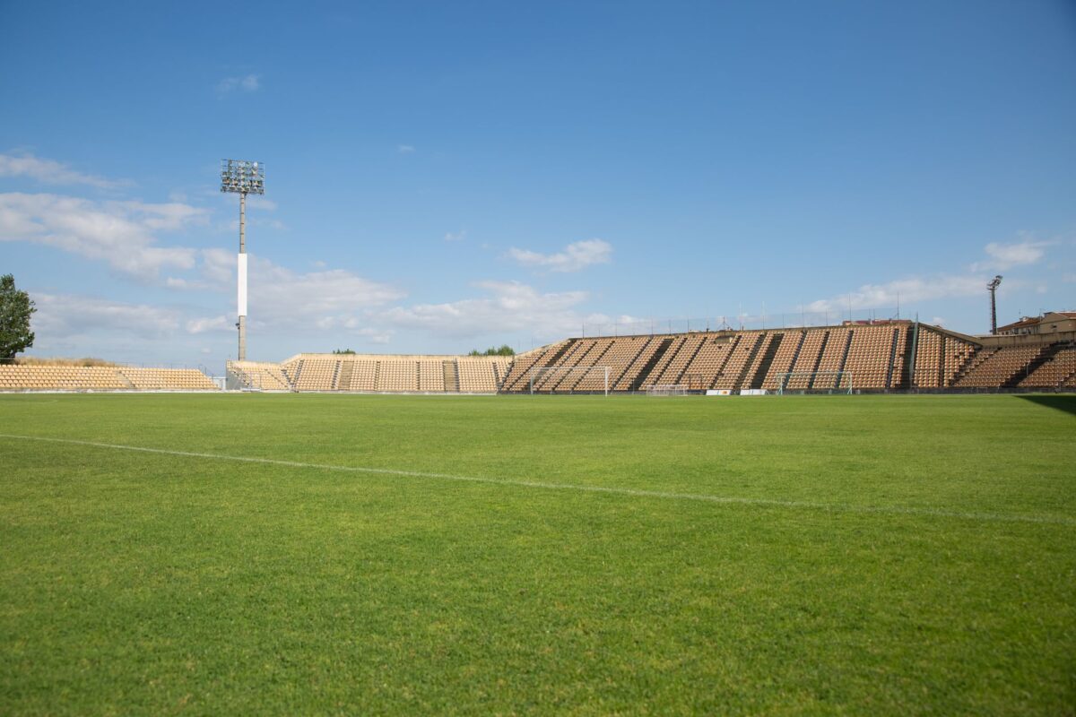 A bright, clear day at an empty football stadium in Portugal, perfect for sports events.